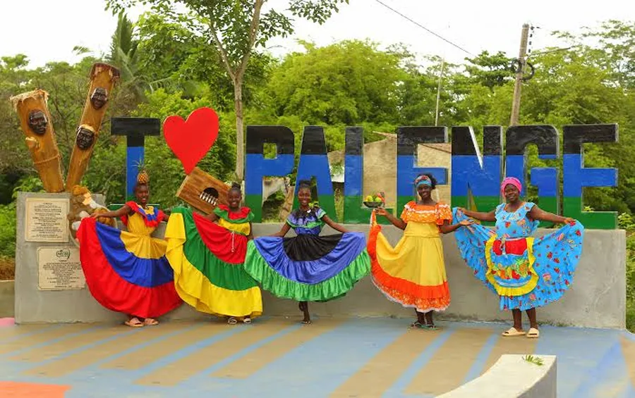 Calle de tierra en San Basilio de Palenque con casas de colores y habitantes conversando